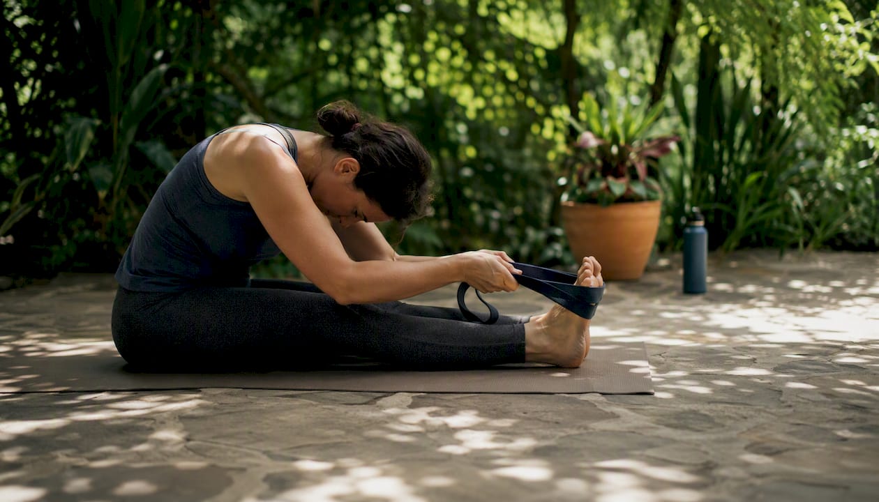 Woman stretching in forward fold with yoga strap