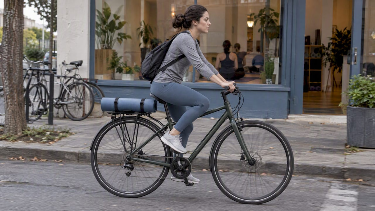 Cyclist riding with yoga mat secured above rear wheel