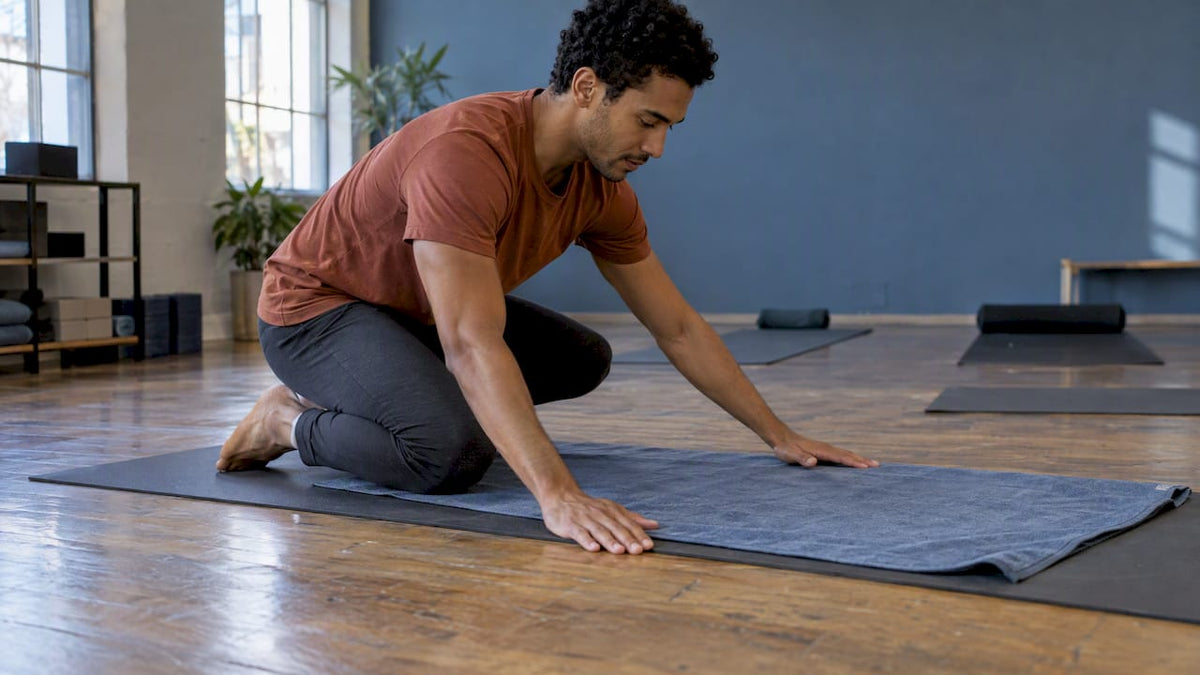 Practitioner smoothing a towel over a yoga mat