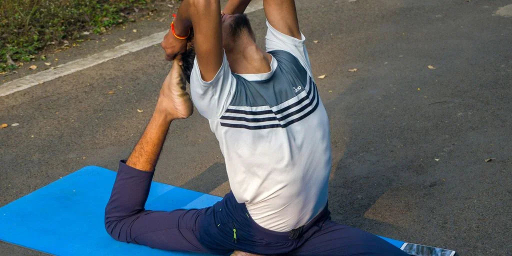 A man doing a yoga pose on a blue mat