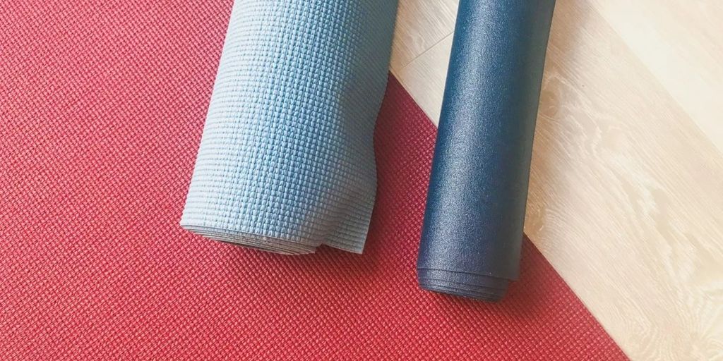 yoga mat cleaner products on wooden floor with fresh flowers and essential oils