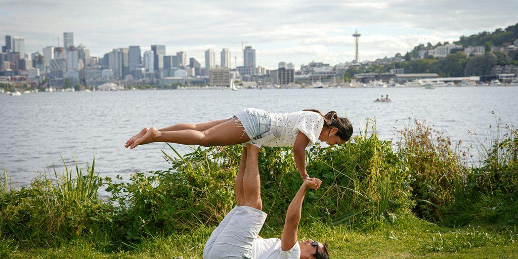 man in white t-shirt and white shorts sitting on green grass field near body of during