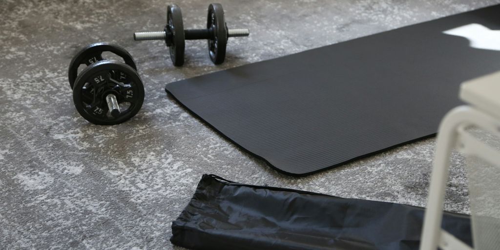 a pair of dumbbells and a black mat on the floor