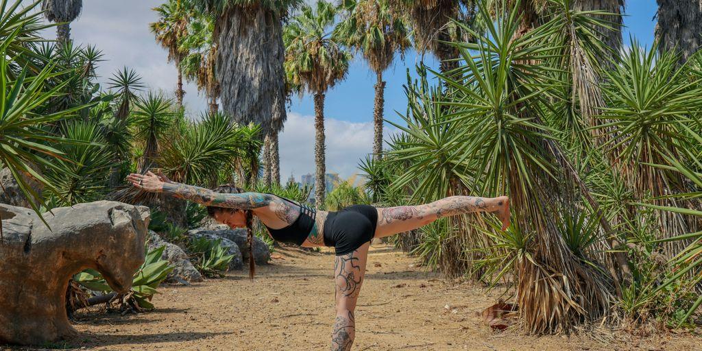 woman in black tank top and black leggings doing yoga on brown wooden log near green