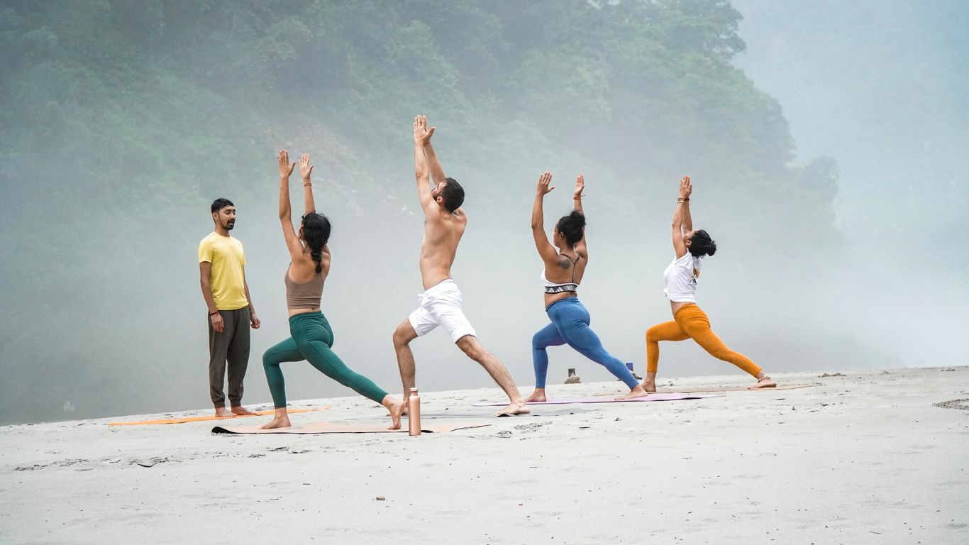 a group of people doing yoga on a beach