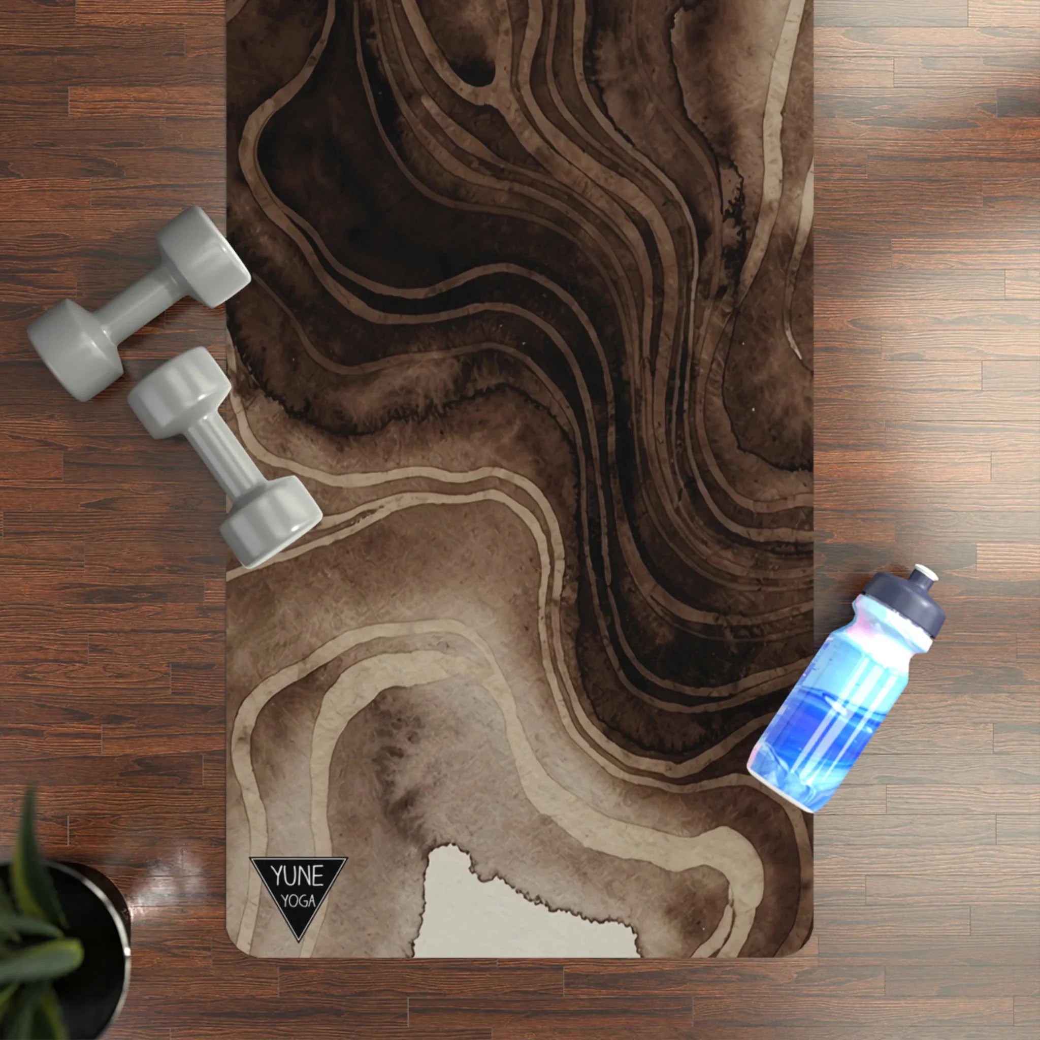 Abstract brown yoga mat on wood floor with hand weights and water bottle