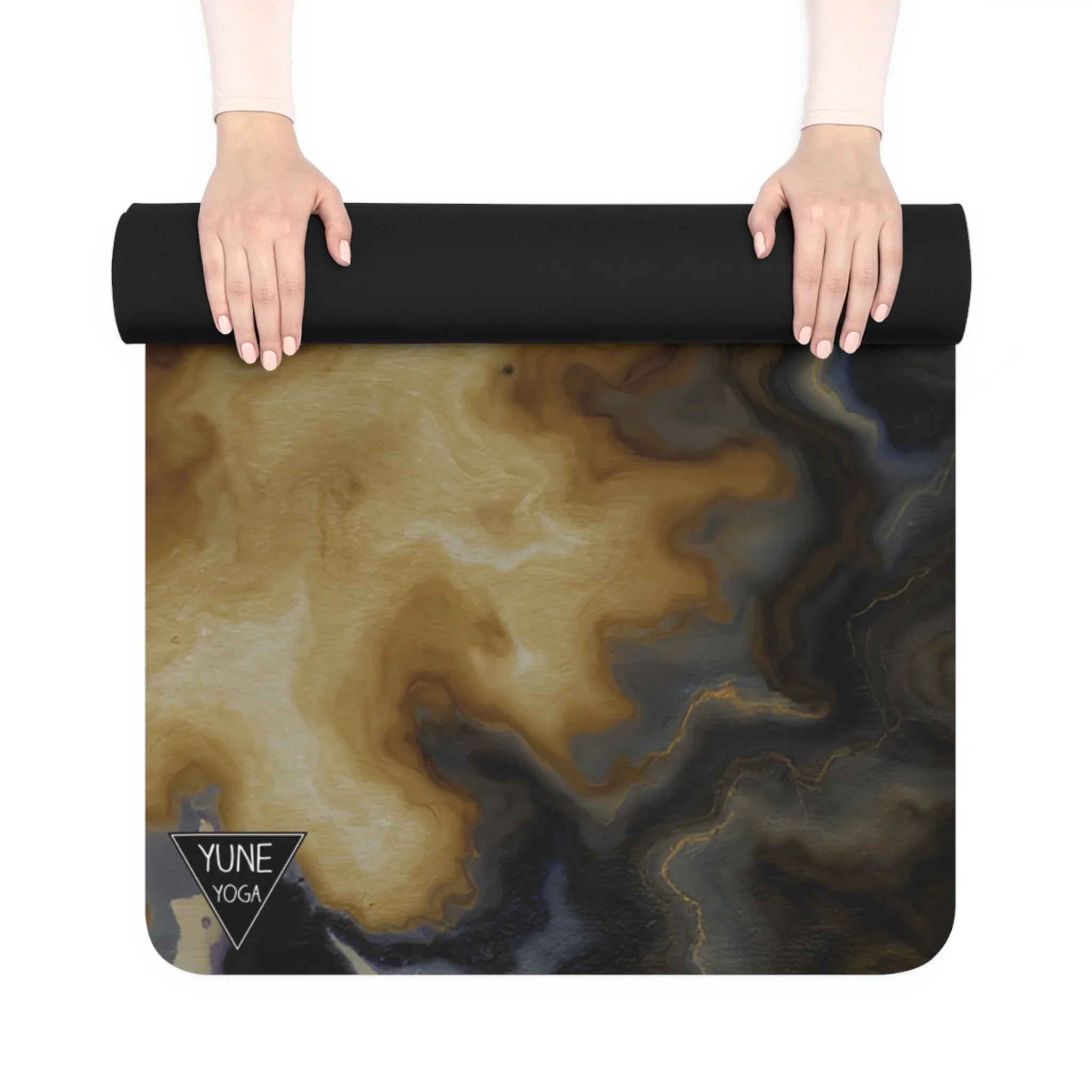 Hands rolling out a marbled design yoga mat with beige and black swirls on a white background