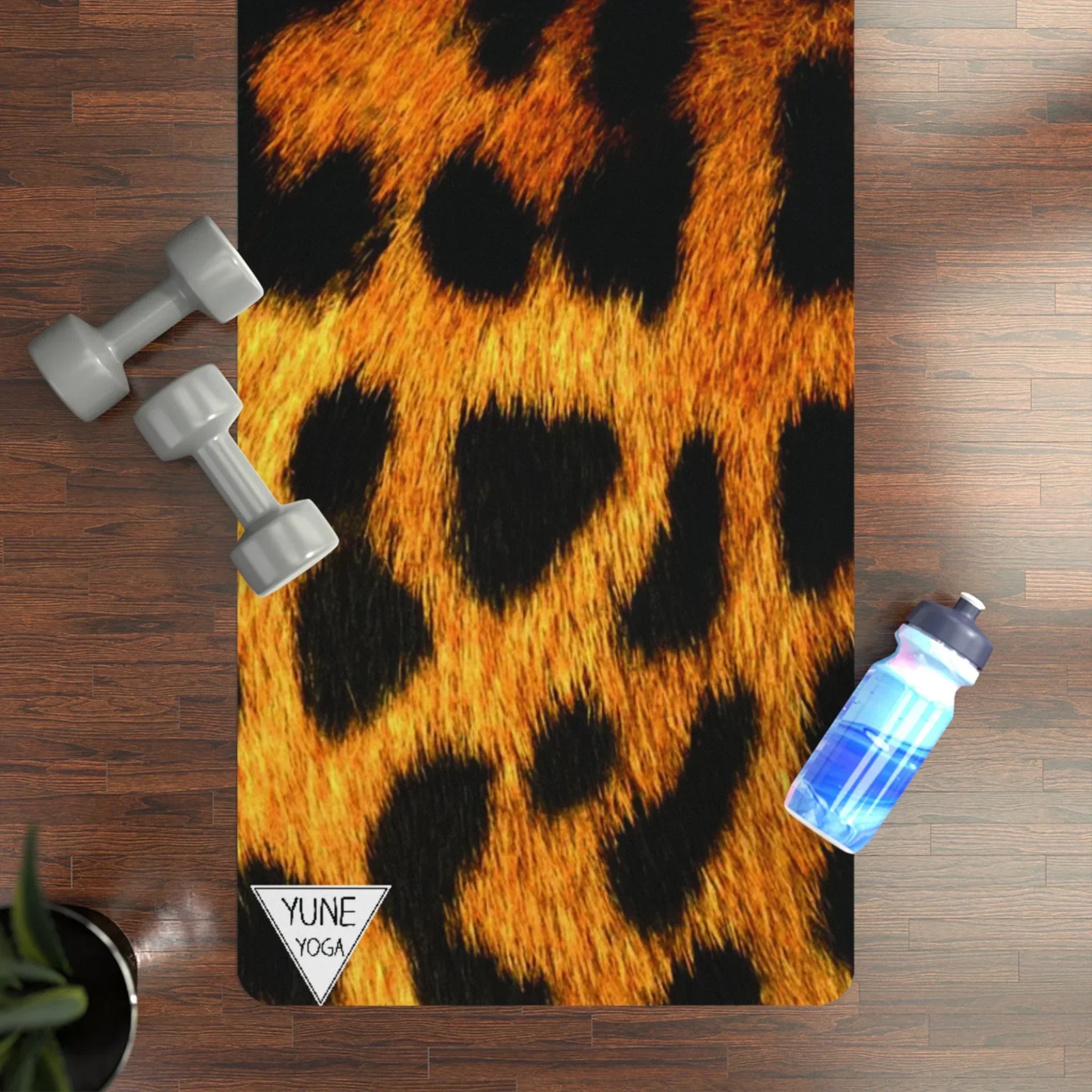 Leopard print yoga mat on wood floor with dumbbells and a water bottle