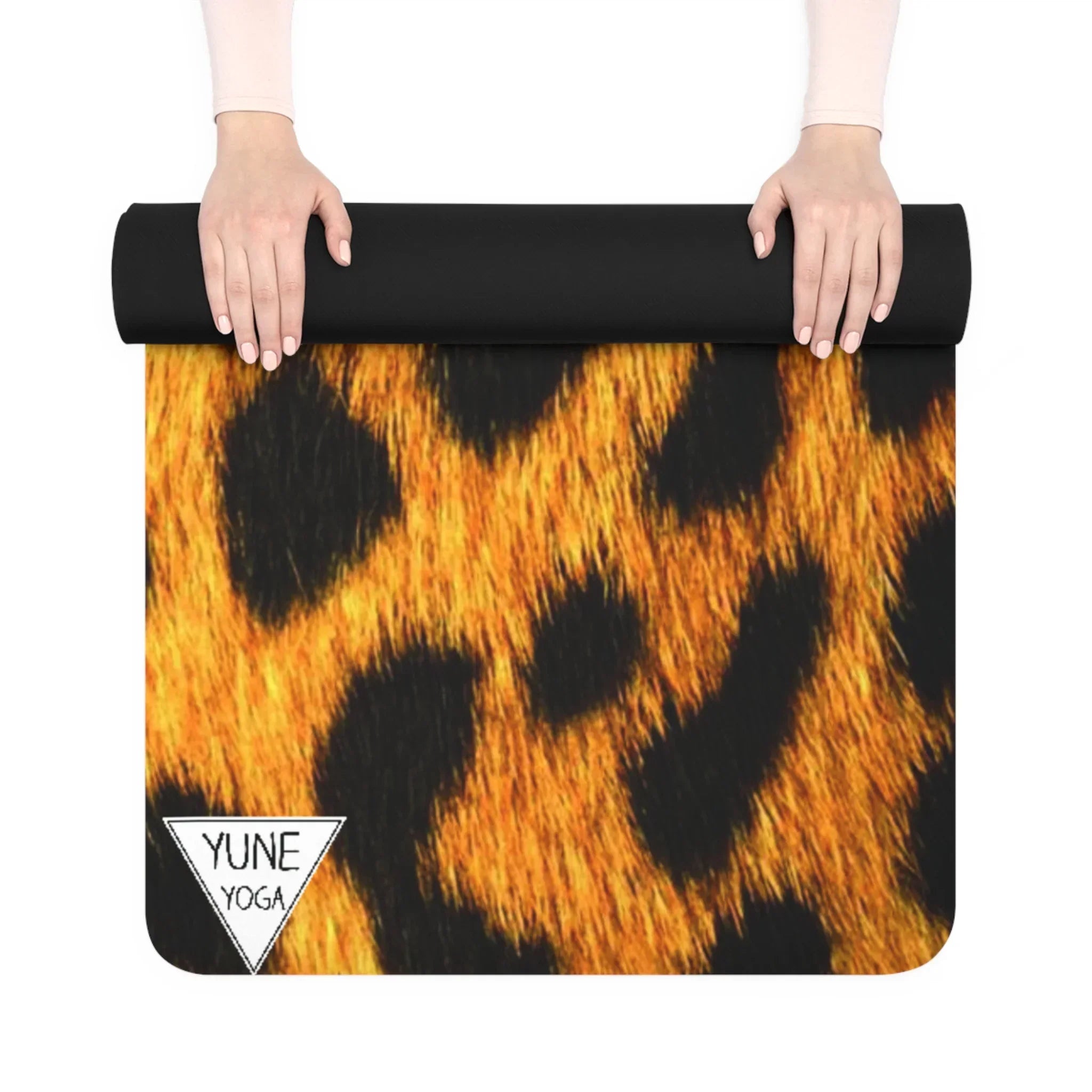 Hands rolling out a yoga mat with a vibrant leopard print pattern and corner logo.