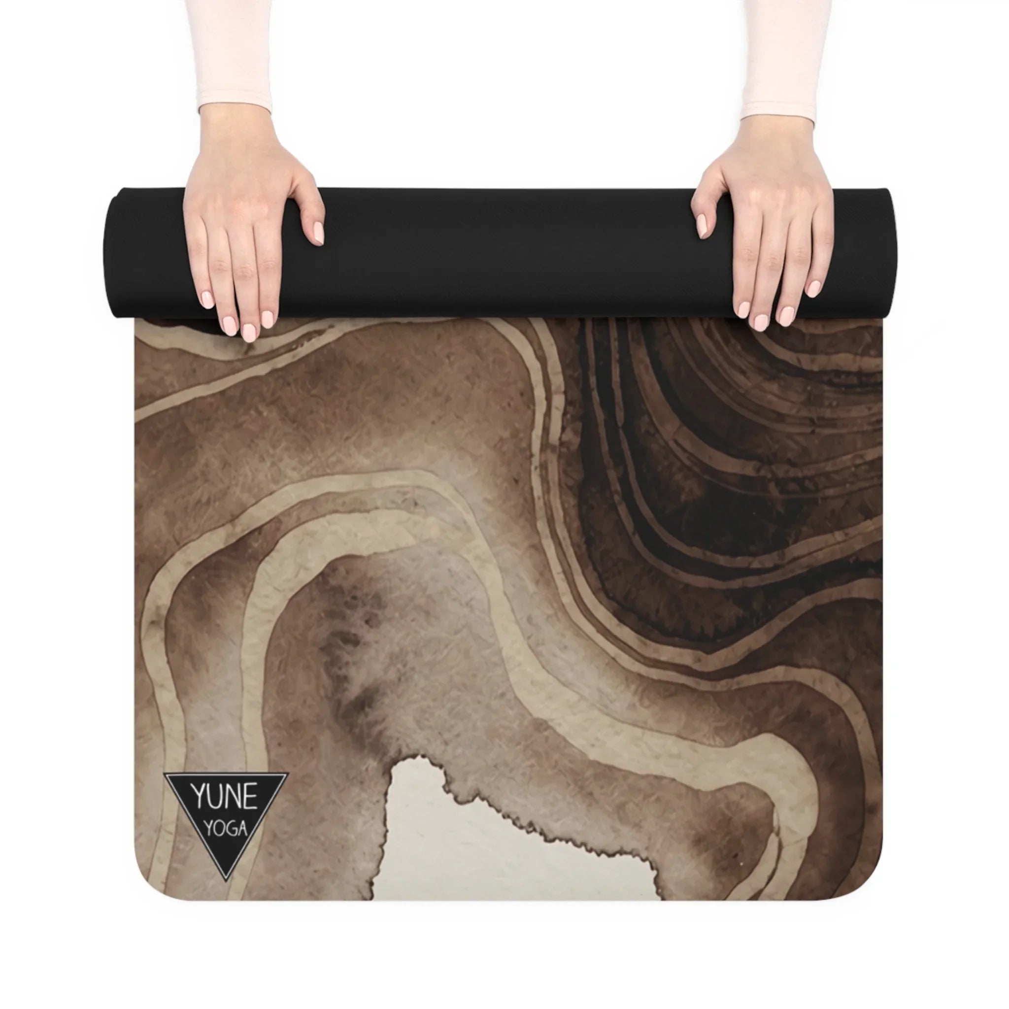 Hands rolling out an abstract brown and black yoga mat with topographic design