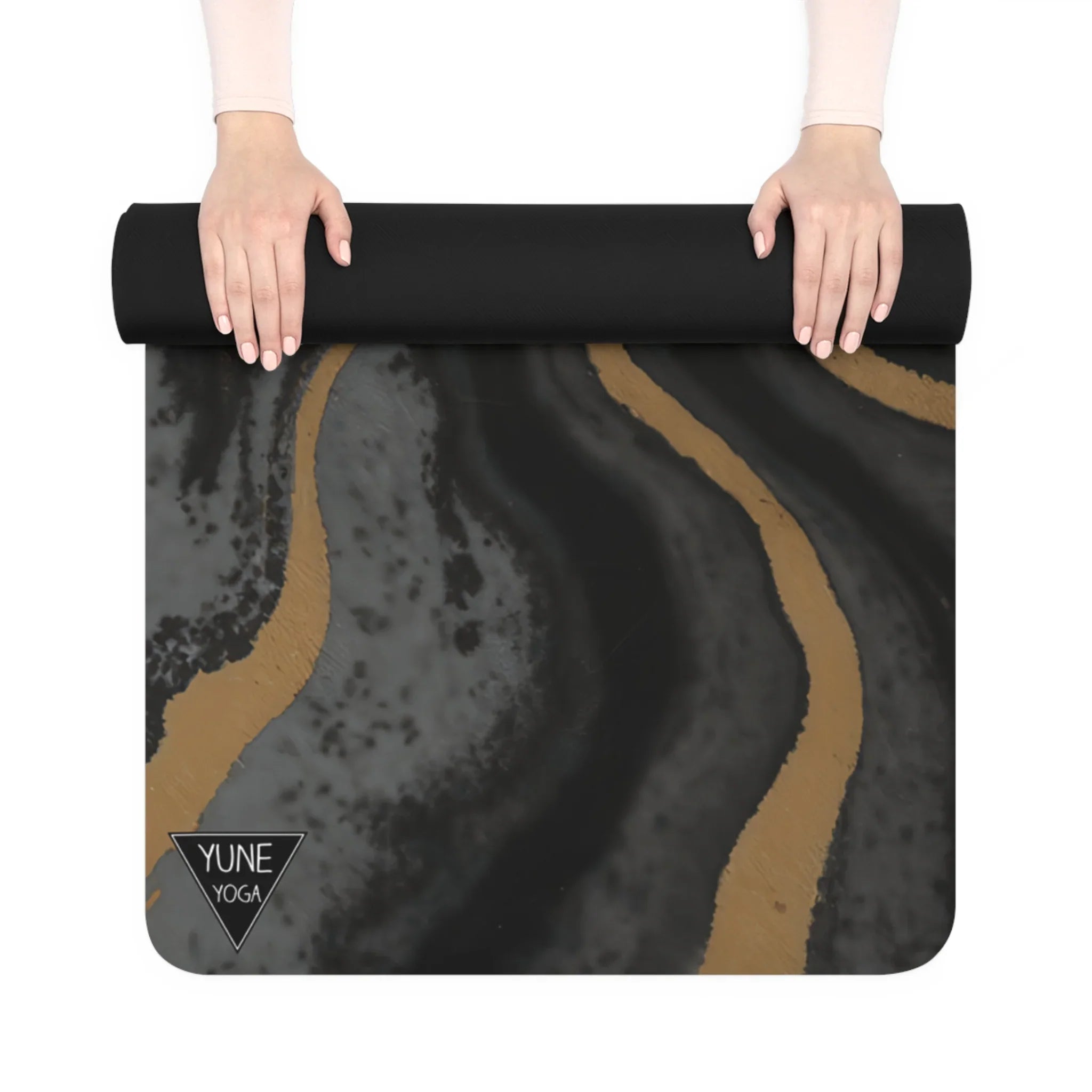 Hands rolling a black and gold abstract yoga mat with marbled pattern