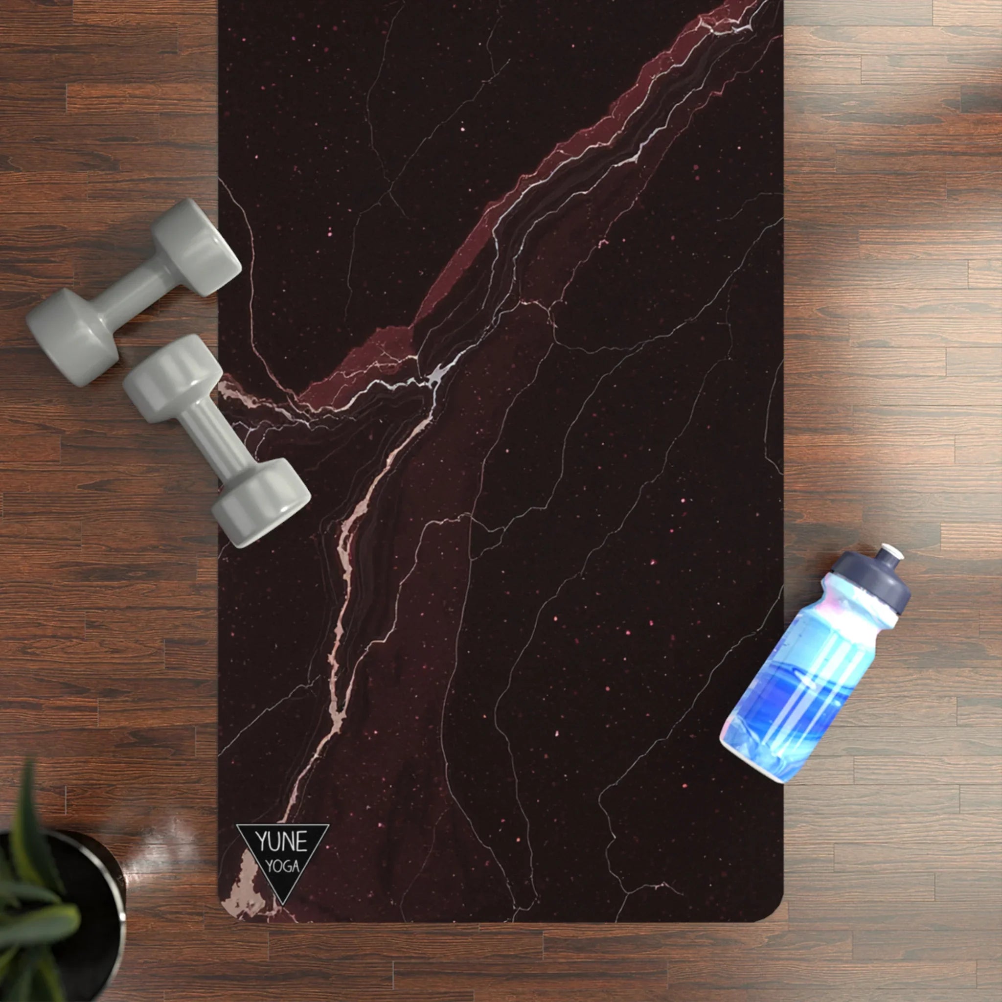 Marble pattern yoga mat on wood floor with dumbbells and water bottle