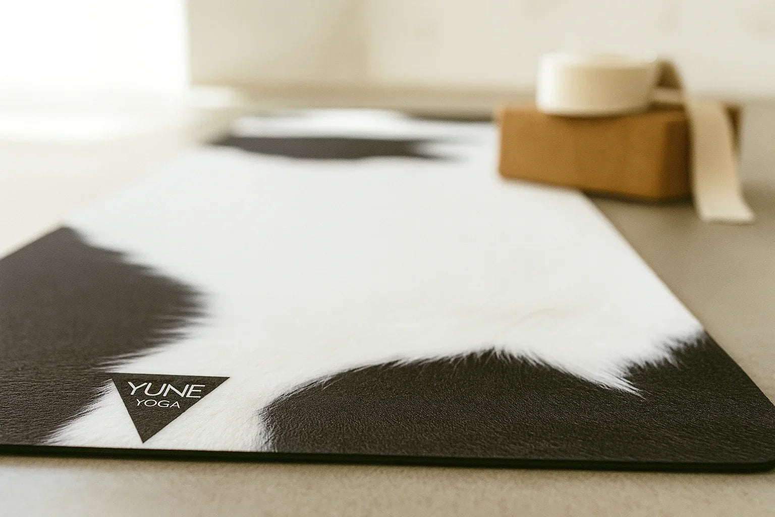 YUNE YOGA mat on a light wooden floor with a blurred background