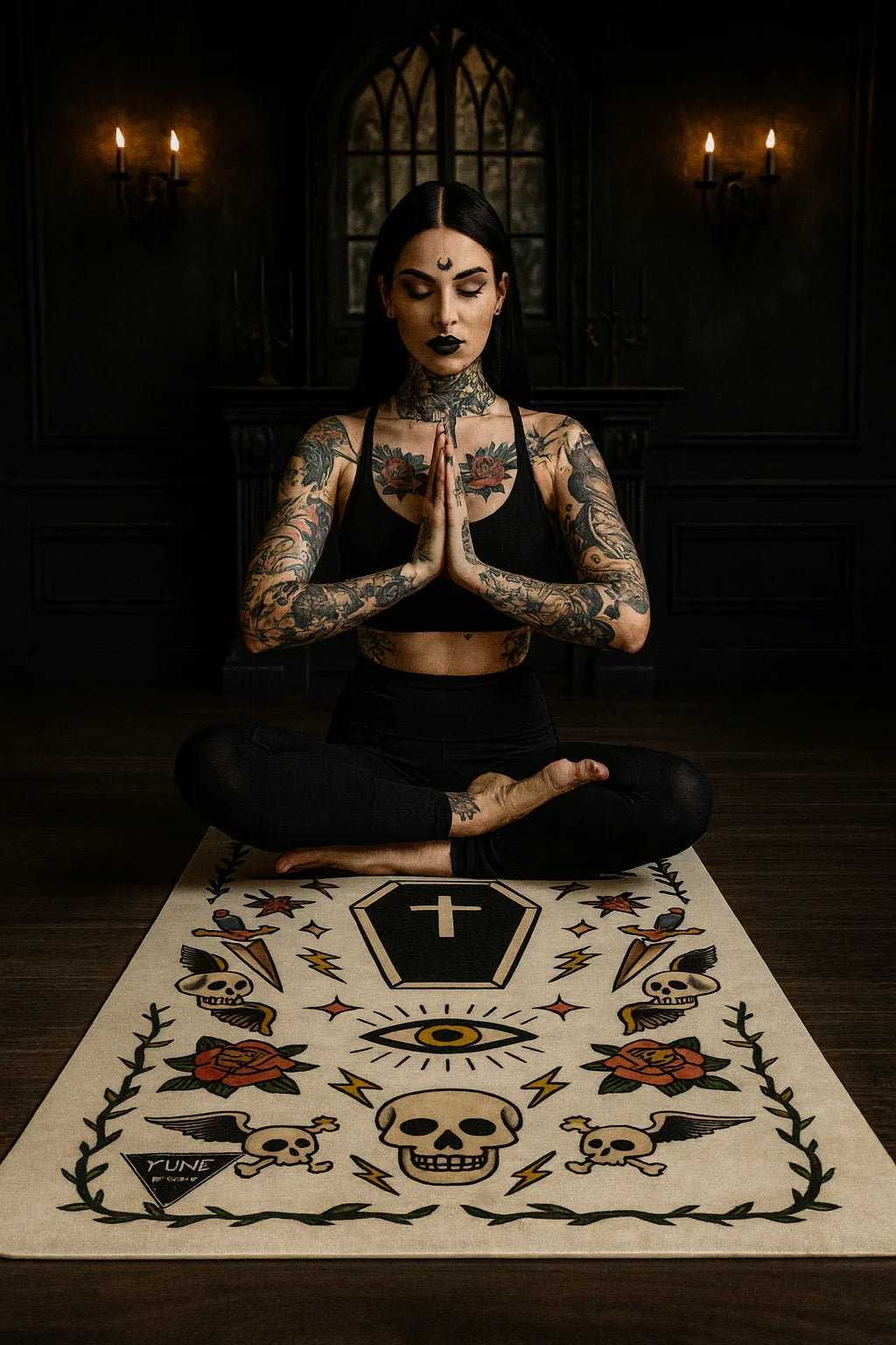 Woman with tattoos meditating on a rug with symbols in a dark room.
