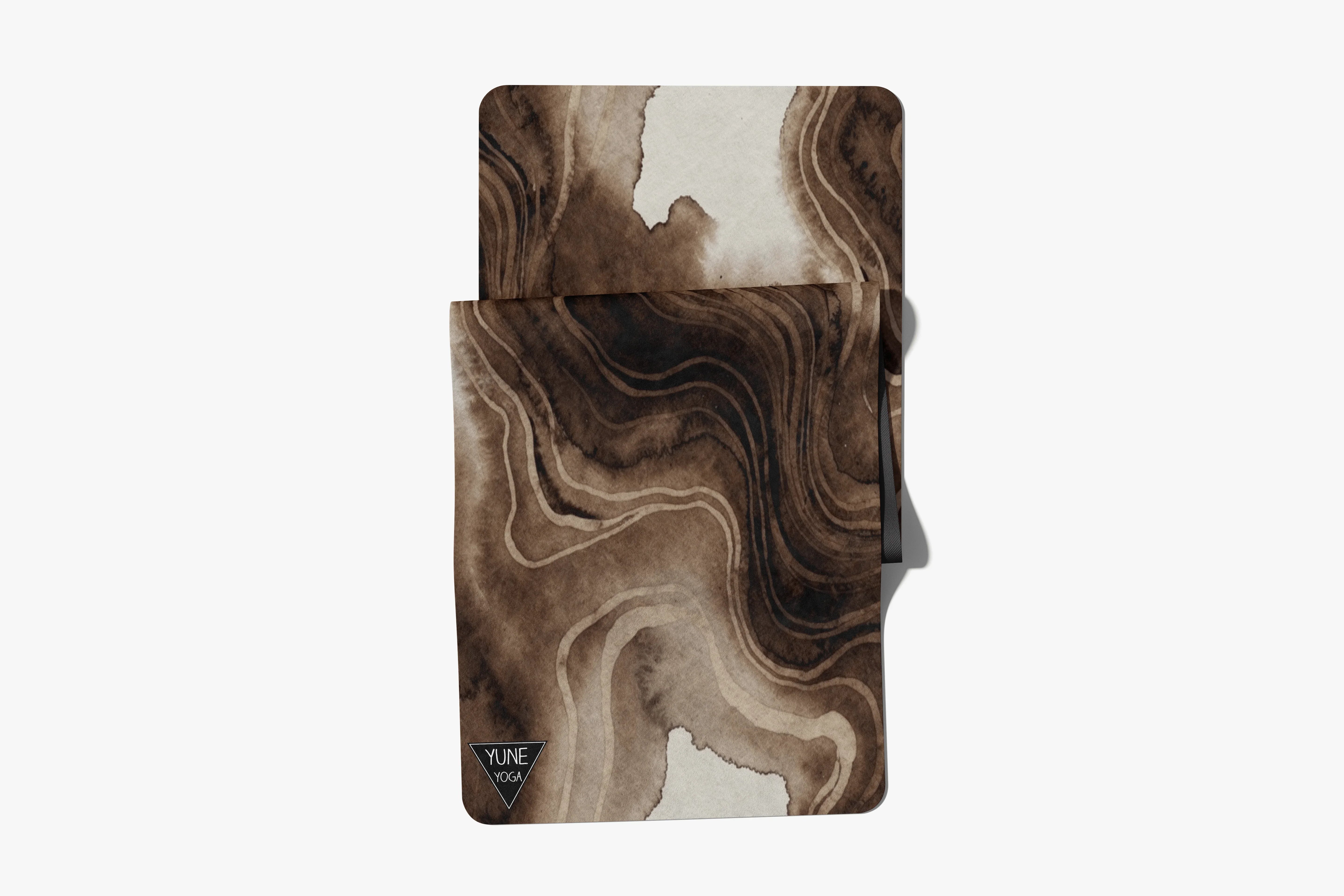 Brown marbled yoga mat with abstract swirl pattern on white background