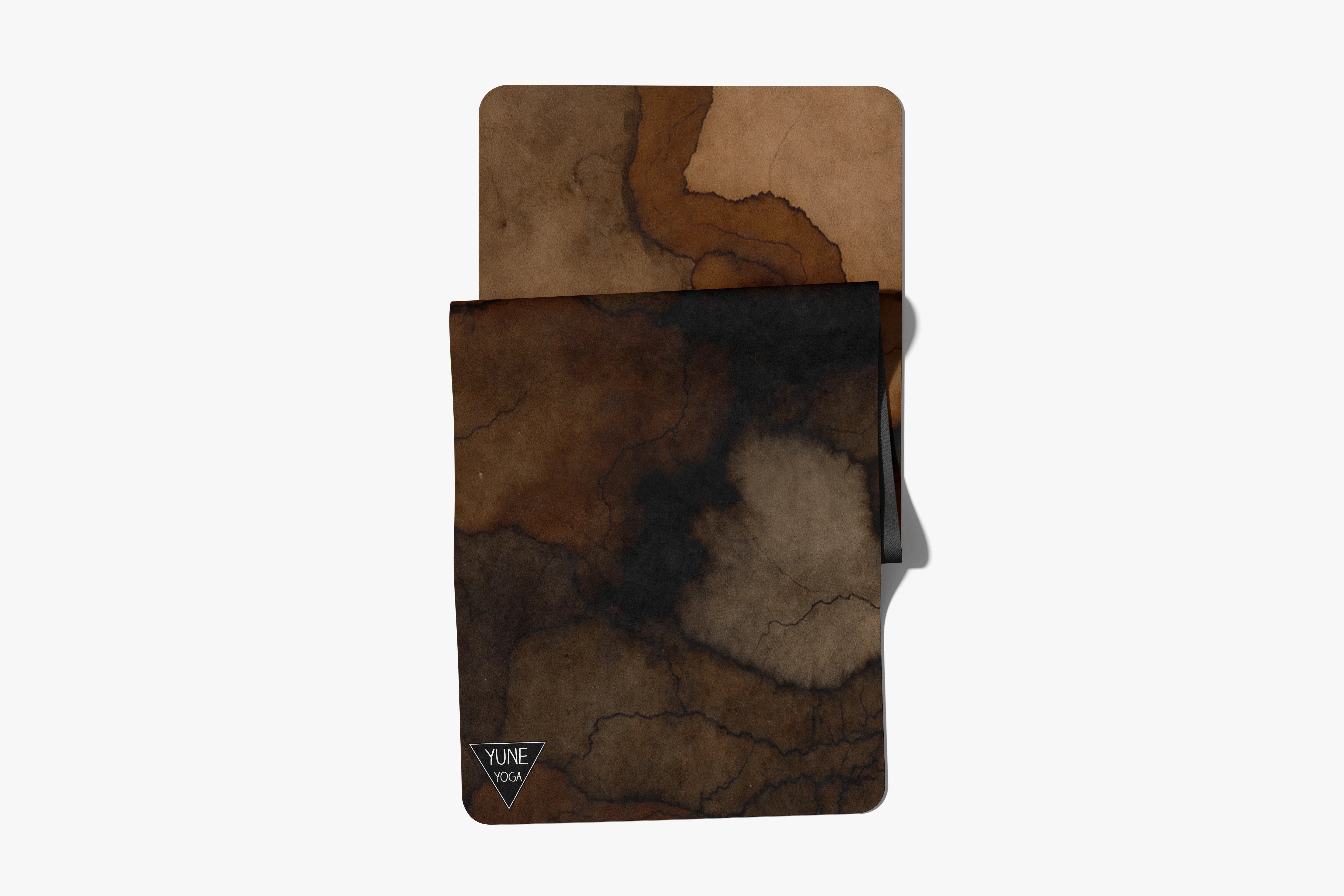 Brown and black marble pattern yoga mat with folded corner on white background