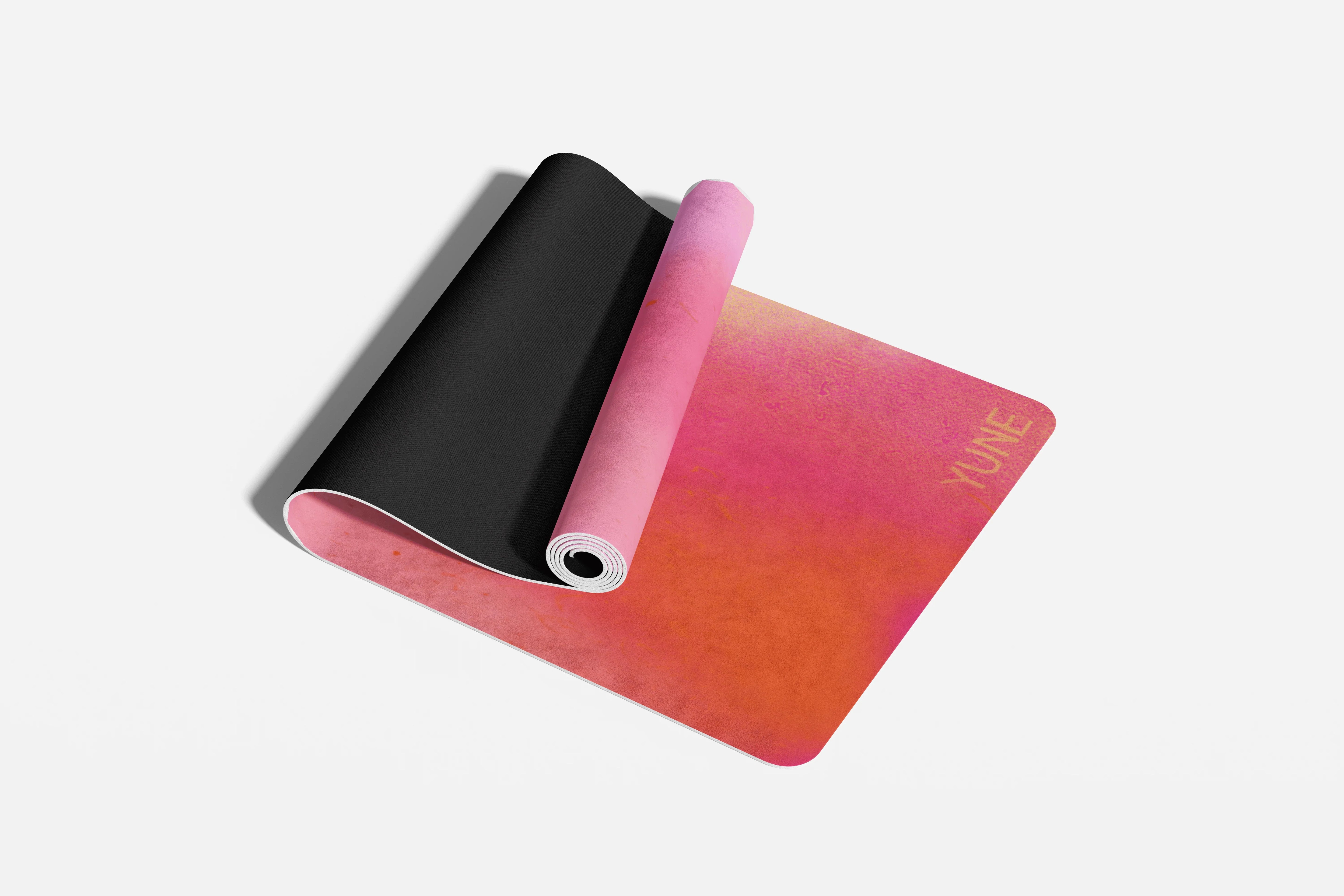 Gradient pink to red yoga mat with black end on a white background