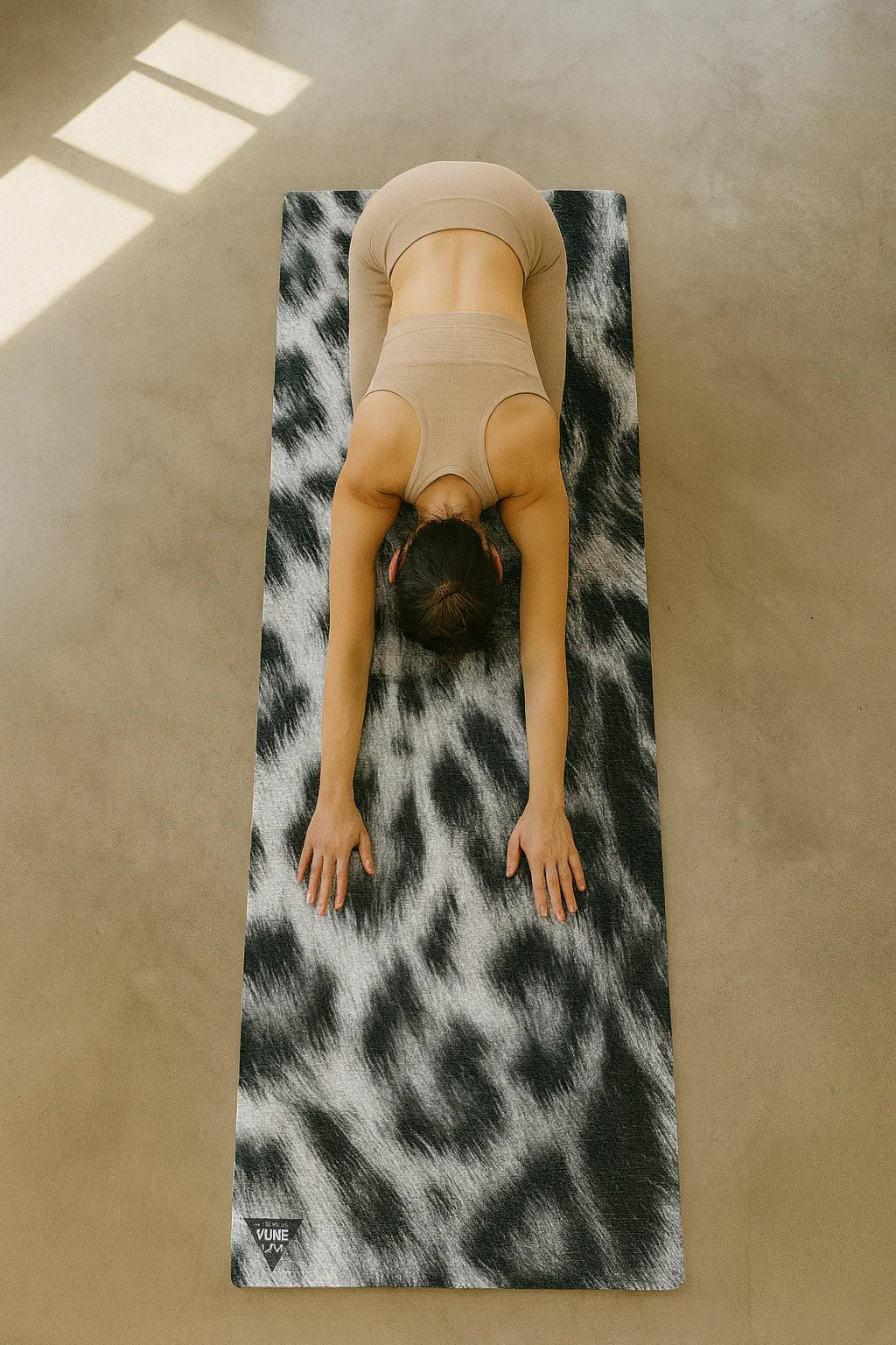 Person practicing yoga on a leopard print mat in a sunlit room