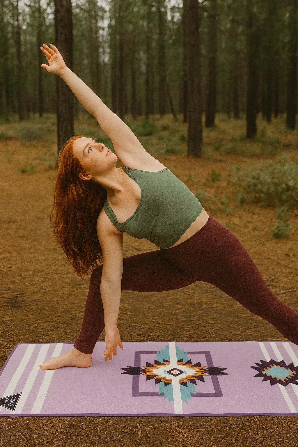 Woman practicing yoga on a purple mat with a forest background