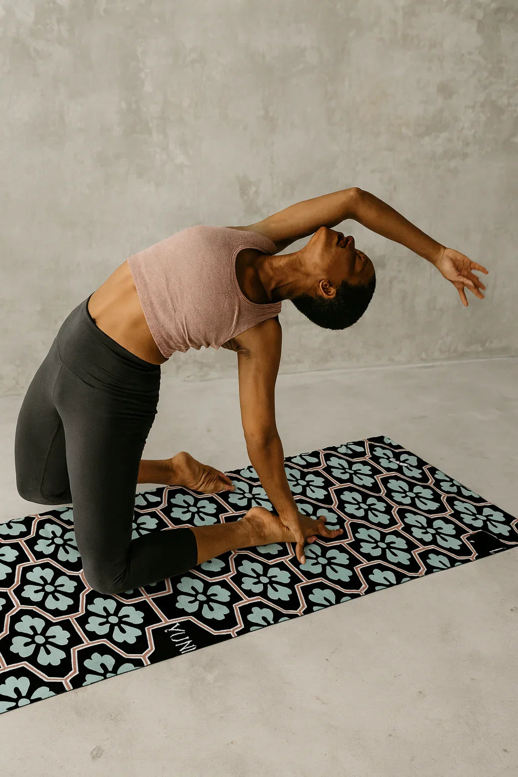 Person practicing yoga on a patterned mat with a gray wall background