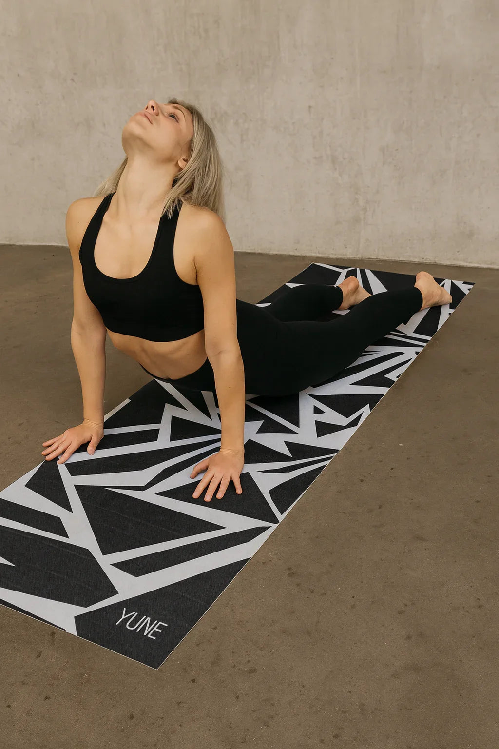 Woman practicing yoga on a black and white patterned Yune mat.