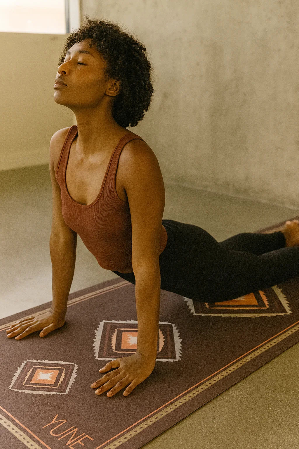 Person practicing yoga on a Yune mat in a room with neutral walls.