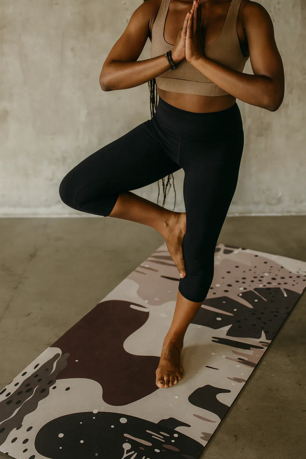 Person practicing yoga on a patterned mat with a neutral background