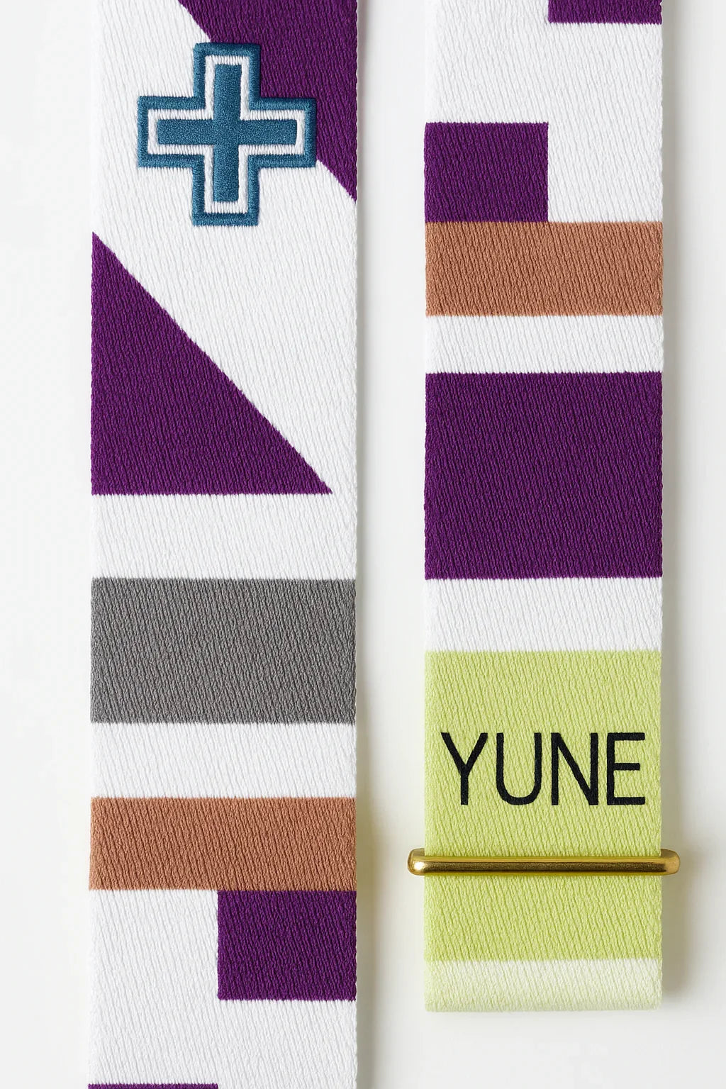 Colorful patterned strap with geometric design and 'YUNE' branding on a white background