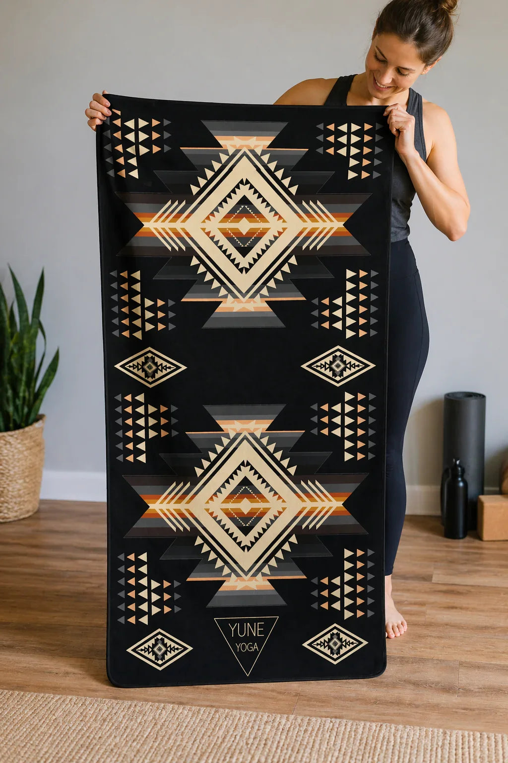 Woman holding patterned yoga mat with geometric design in a modern home studio