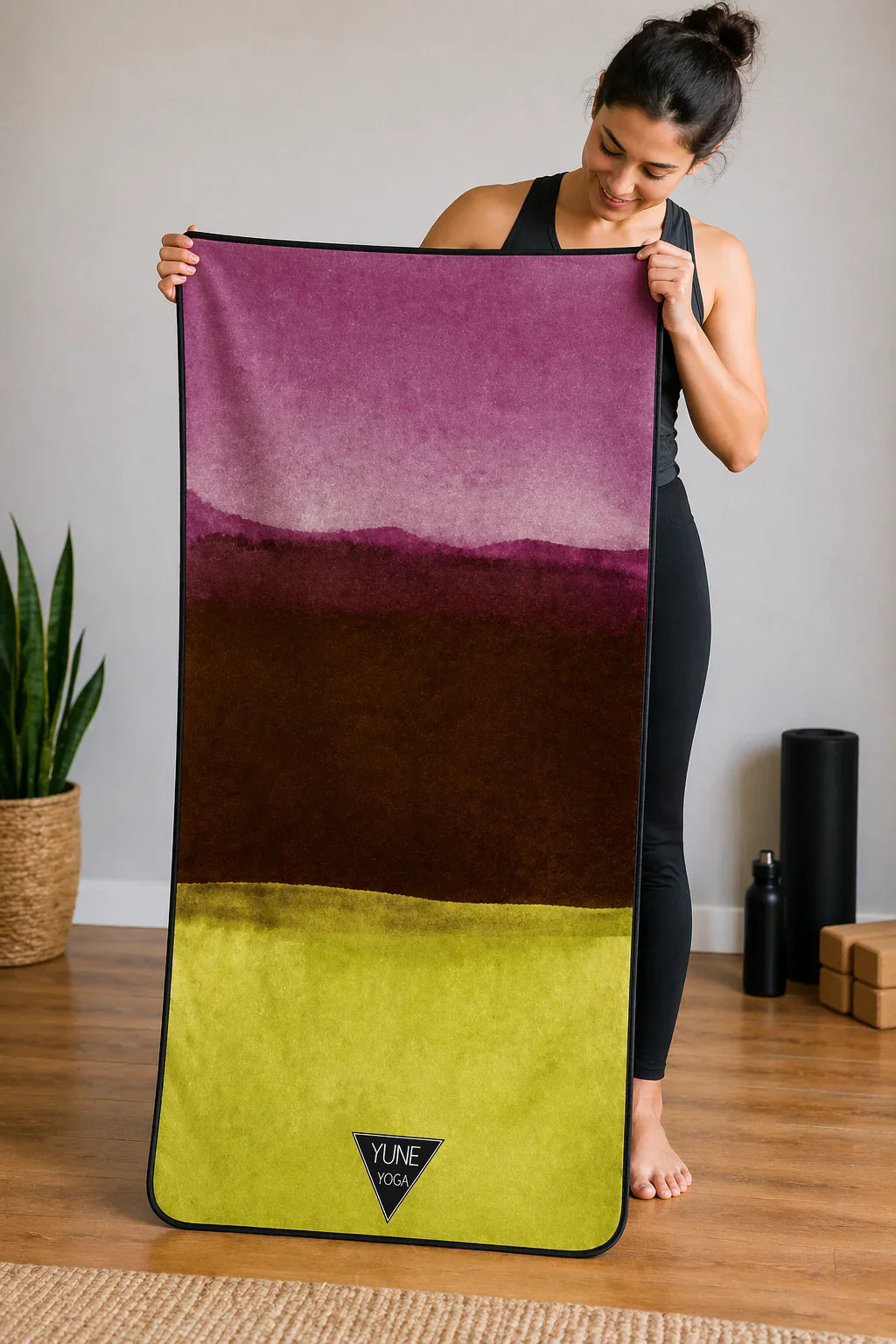 Woman holding colorful yoga mat with pink, brown, and green design in calm studio