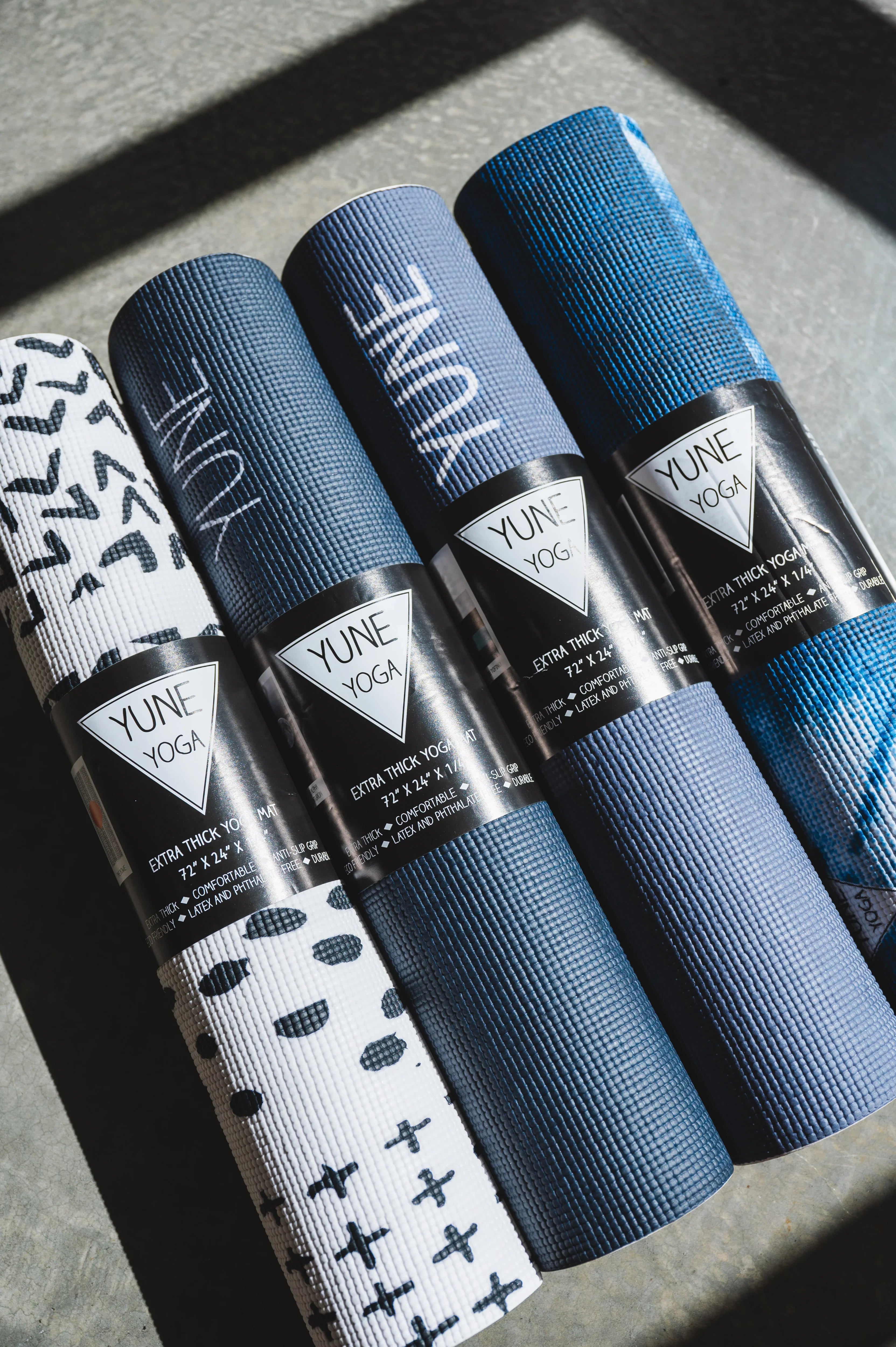 Four yoga mats with Yune Yoga branding on a textured surface