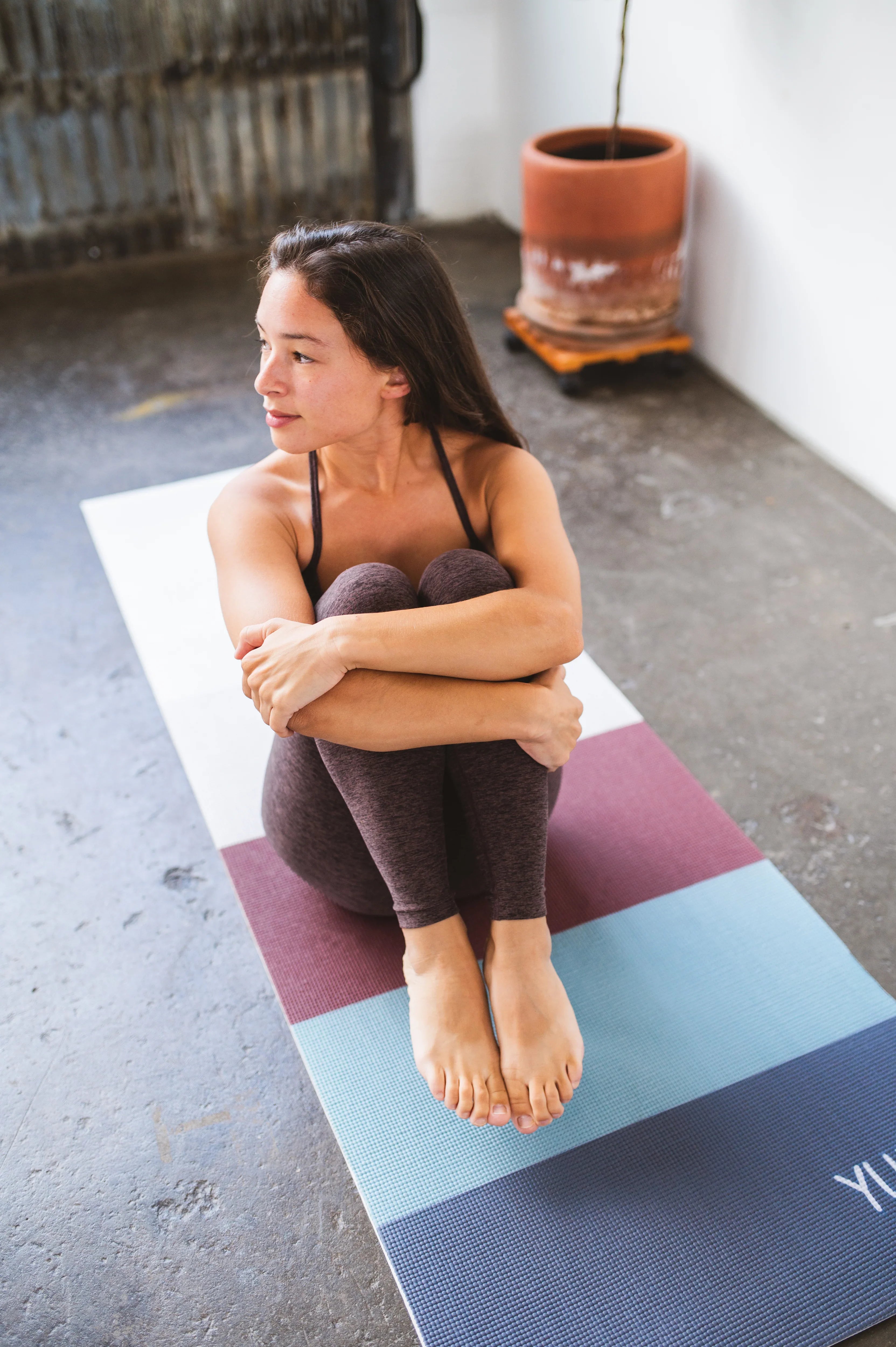 Woman sitting on a colorful yoga mat in an indoor setting