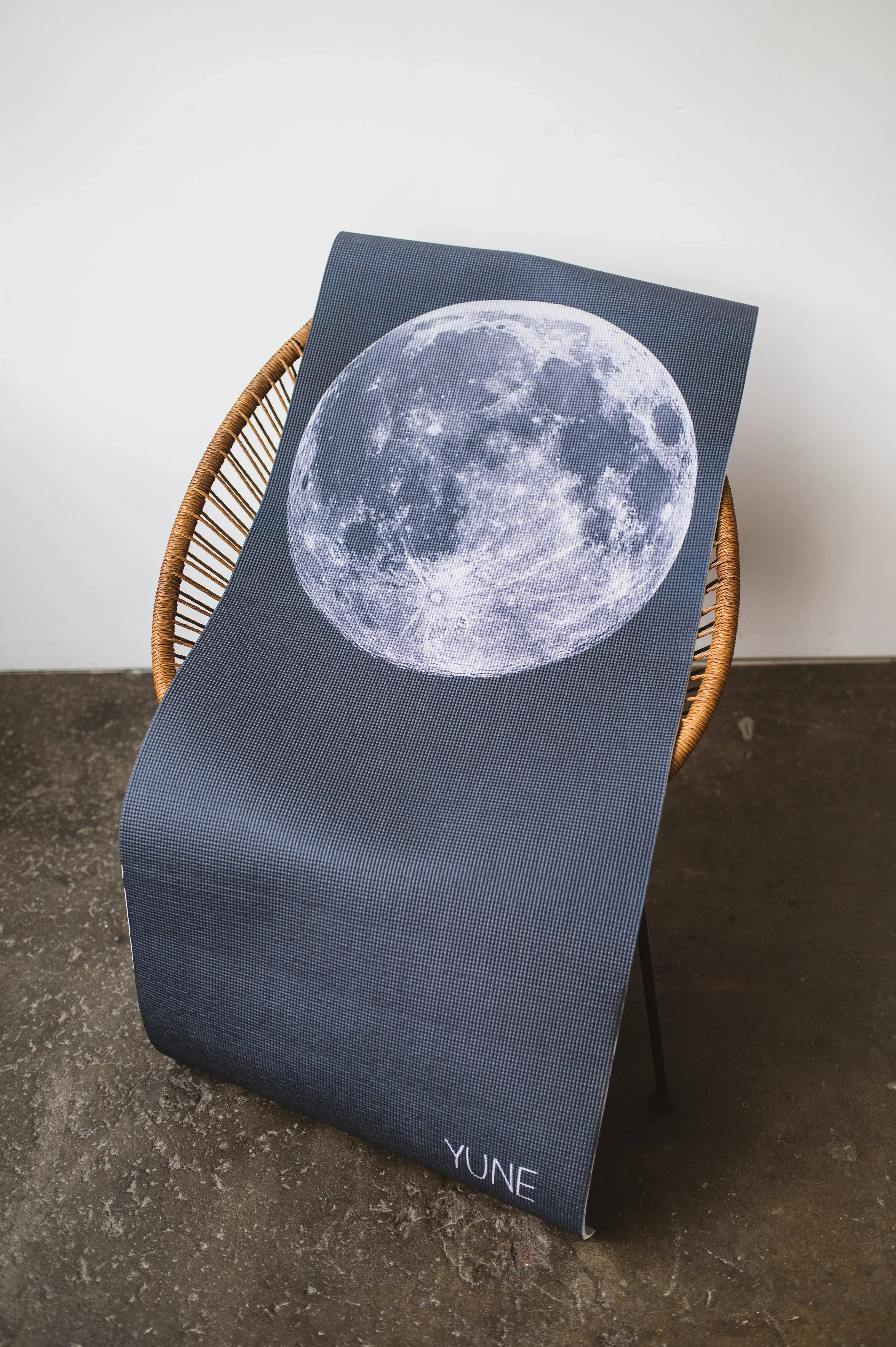 Dark blue cushion with moon design on a chair against a white wall