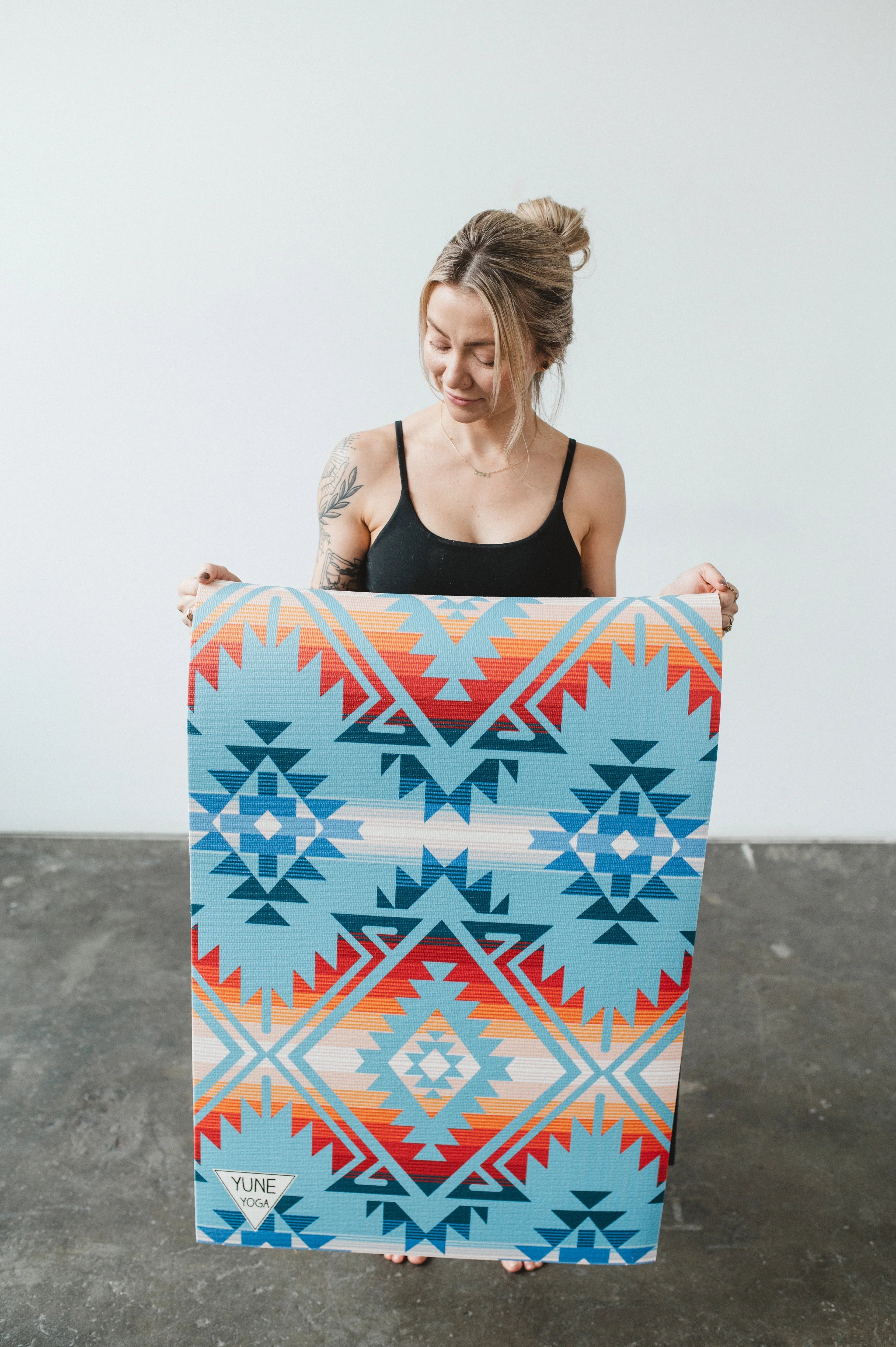 Woman holding a colorful patterned towel against a plain background
