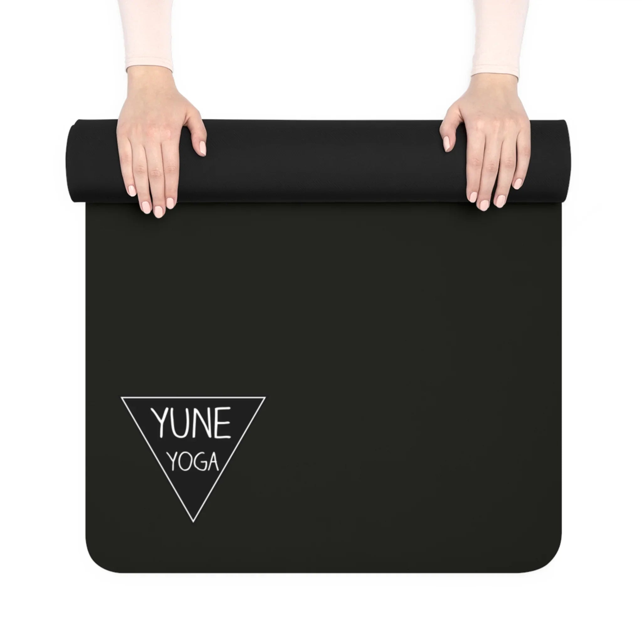 Black yoga mat with 'YUNE YOGA' logo held by hands on a white background
