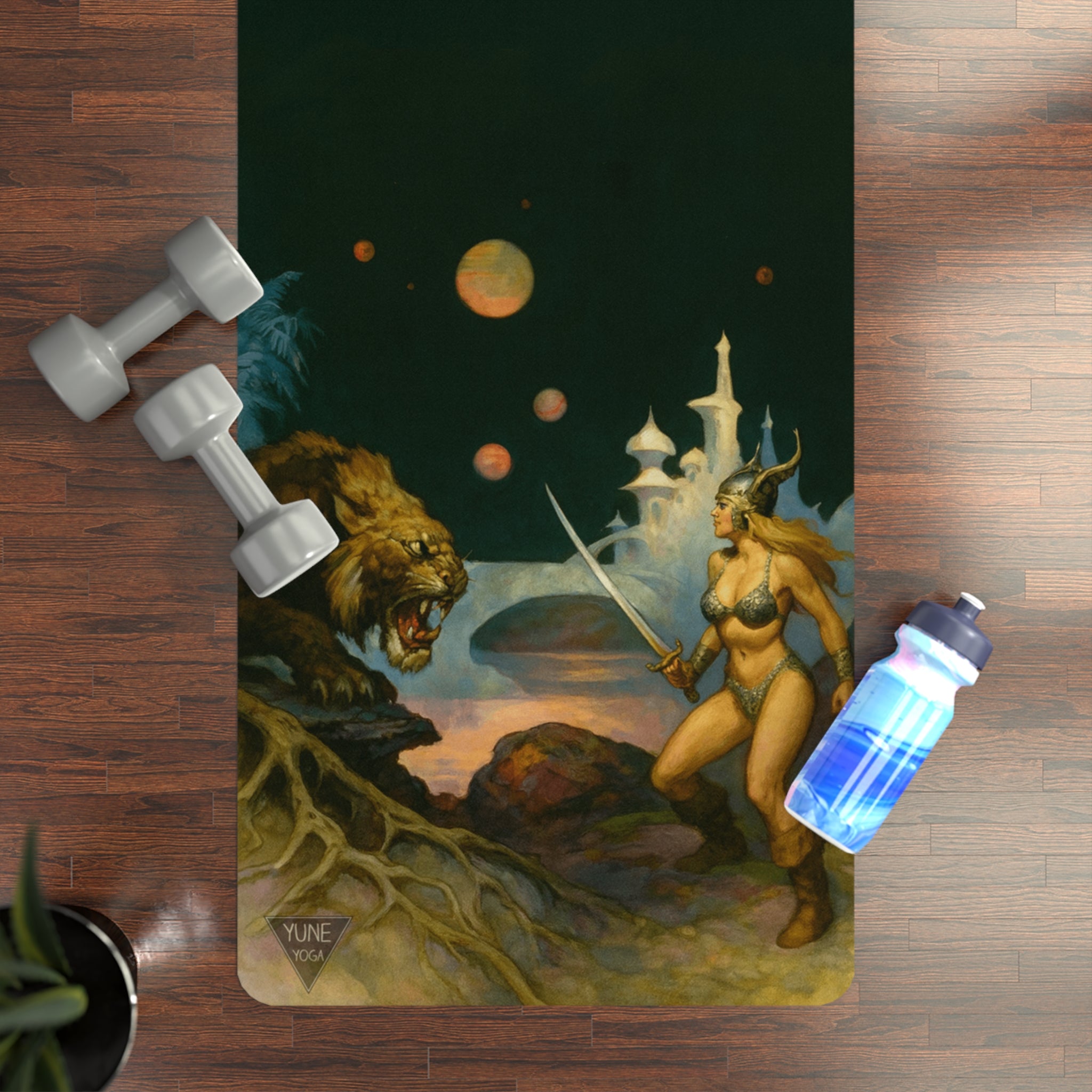 Yoga mat with fantasy design featuring a woman with a sword and a lion, placed on a wooden floor with dumbbells and a water bottle.