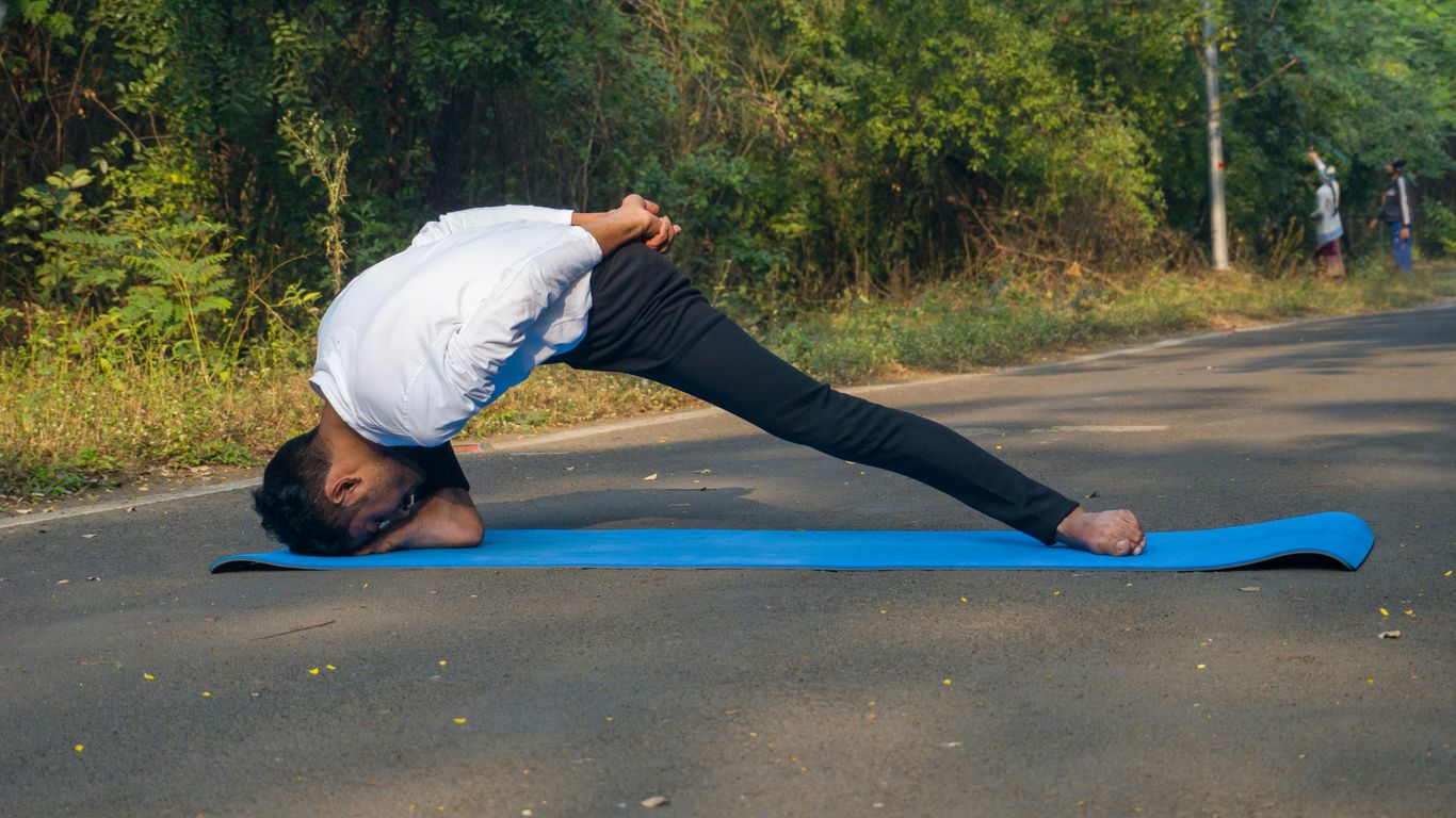 A man doing a yoga pose on a blue mat