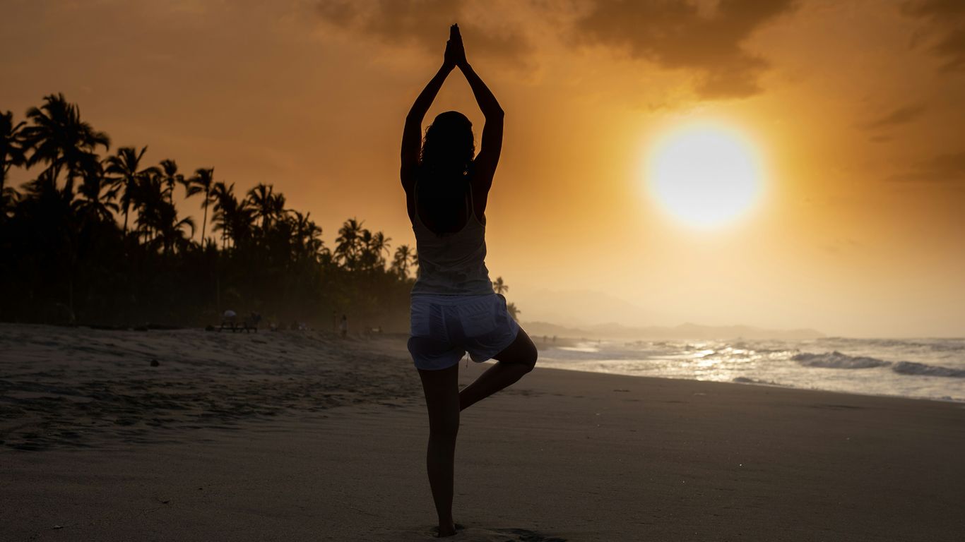 woman in white tank top and white shorts standing on beach during sunset