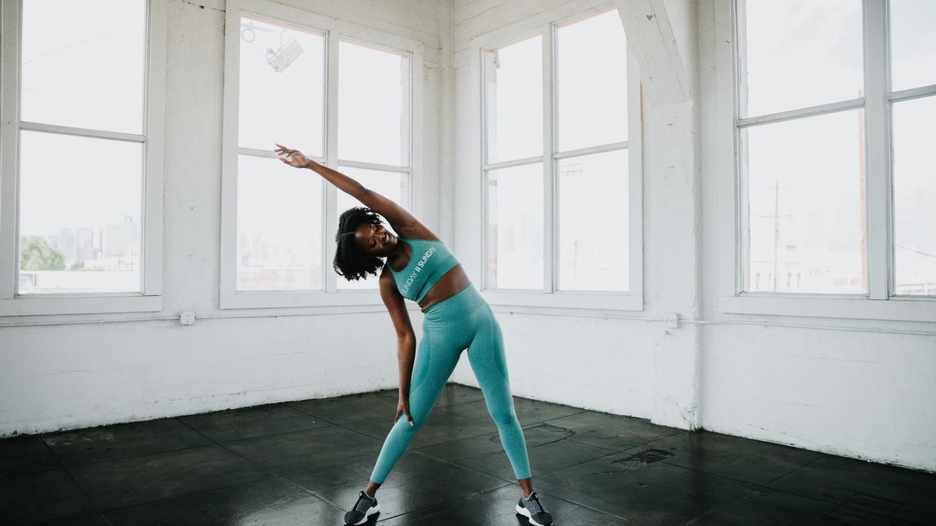 a woman in a blue sports bra top and leggings doing a yoga pose