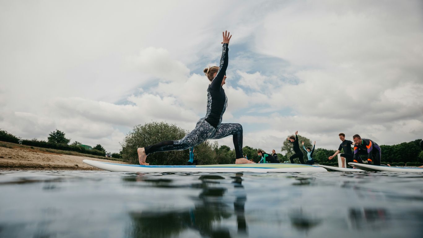 woman in black tank top and black leggings doing yoga on blue yoga mat on water