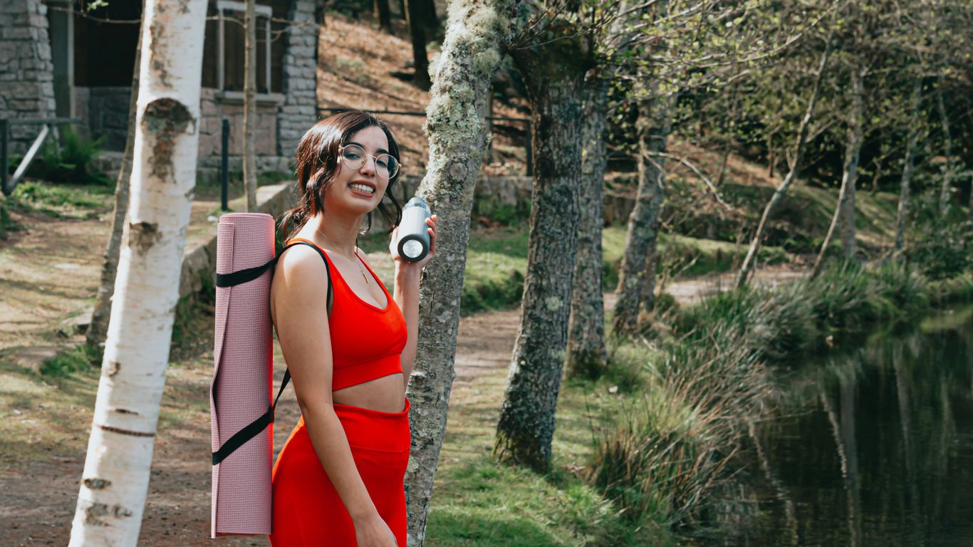 woman in red tank top standing beside tree