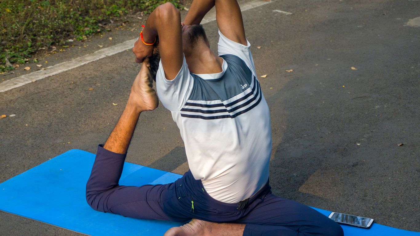 A man doing a yoga pose on a blue mat