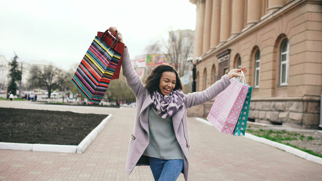 Woman happily holding shopping bags outdoors.