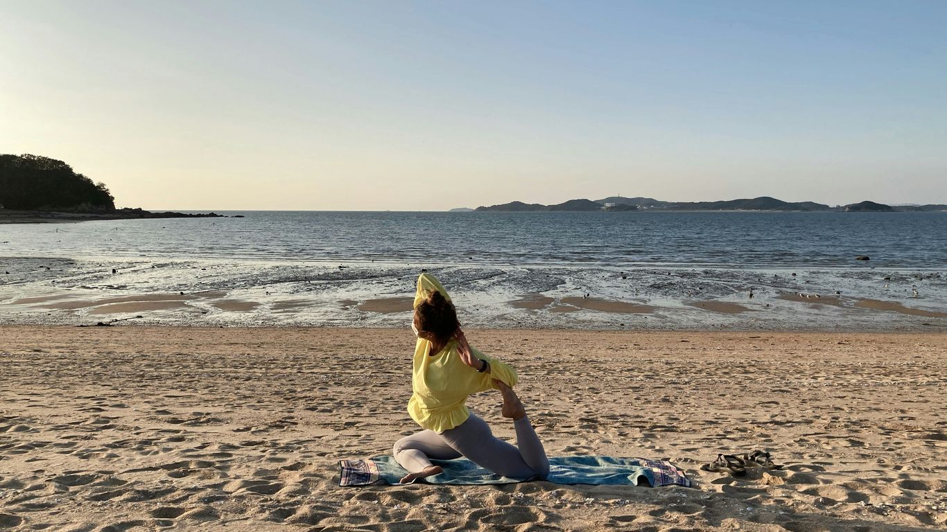 woman in yellow dress sitting on beach shore during daytime