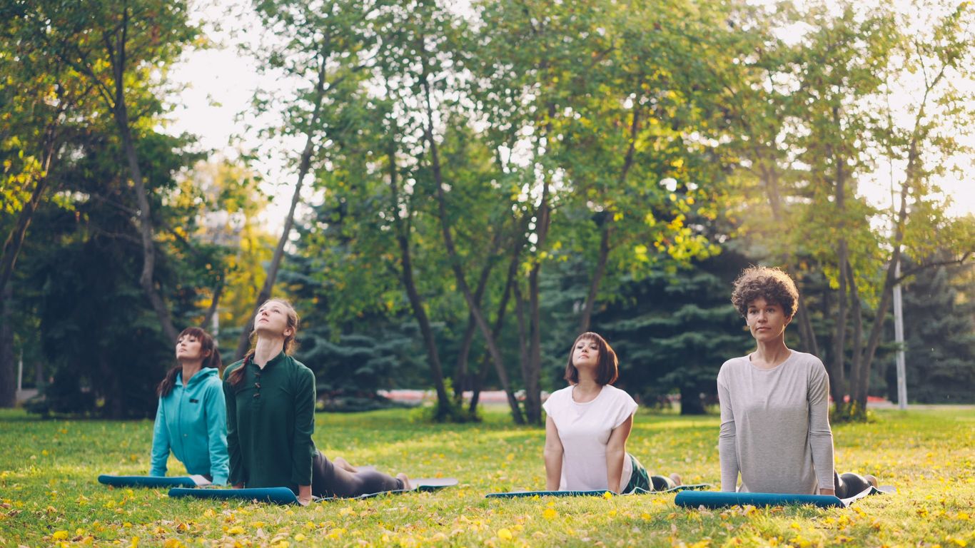 Four people practicing yoga in a park