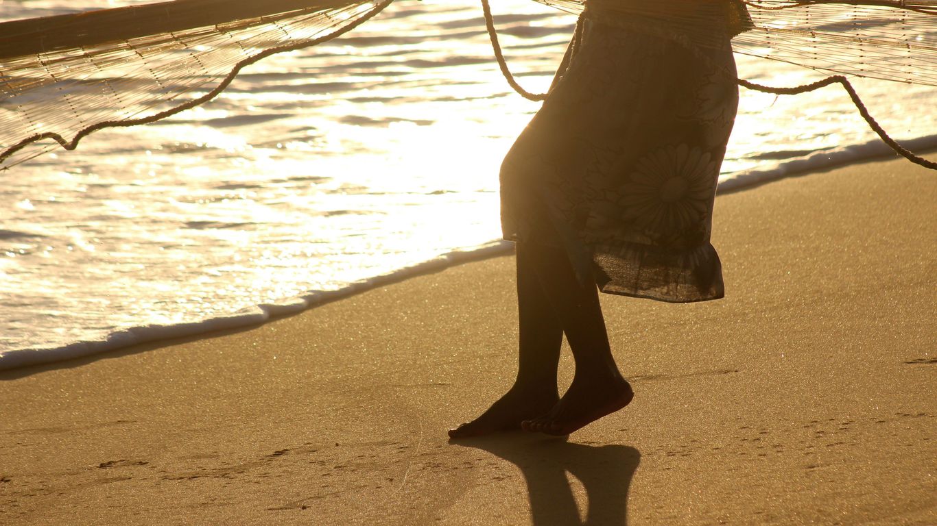 person in black pants standing on beach during daytime