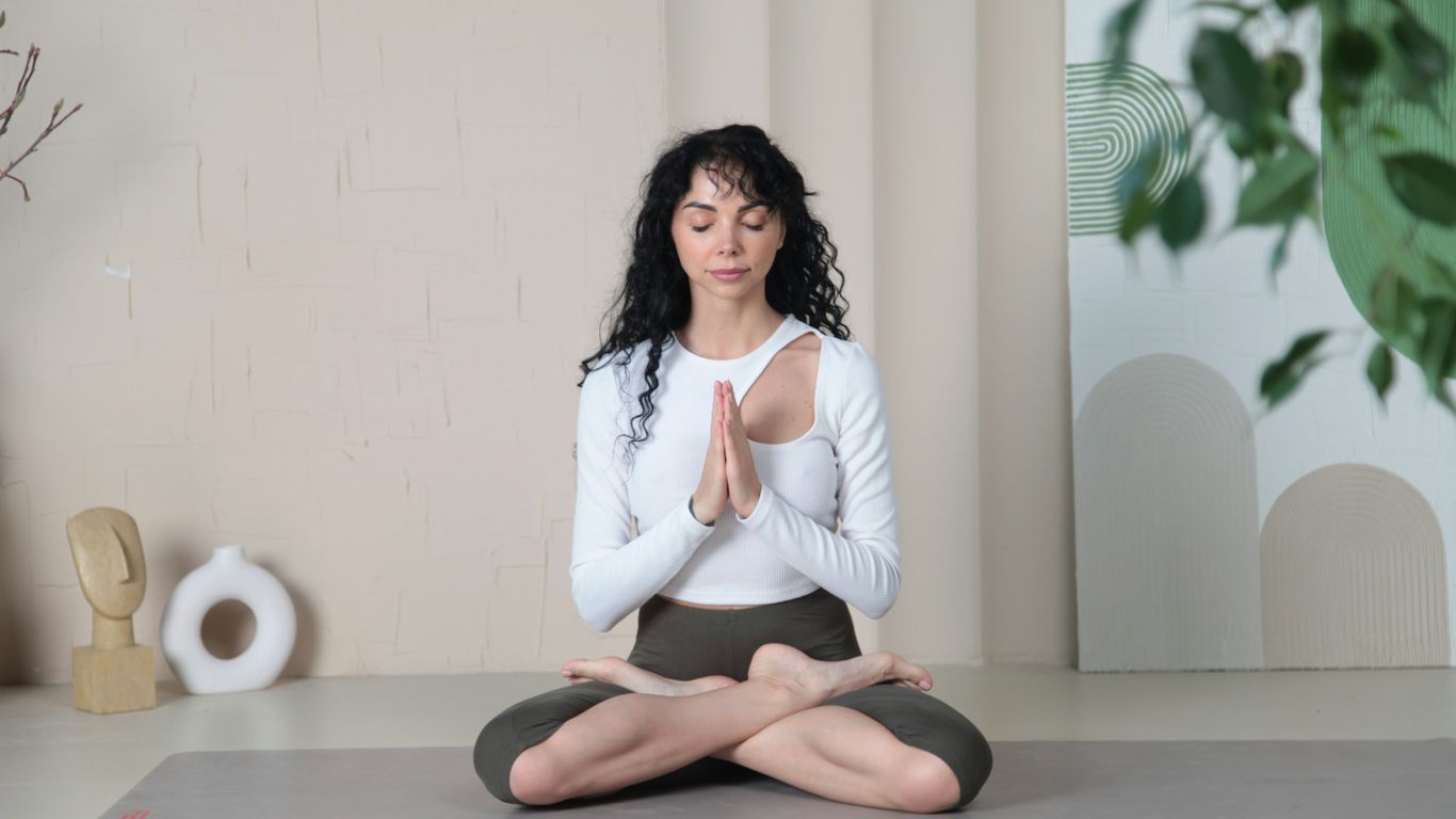 a woman sitting in a yoga position with her eyes closed
