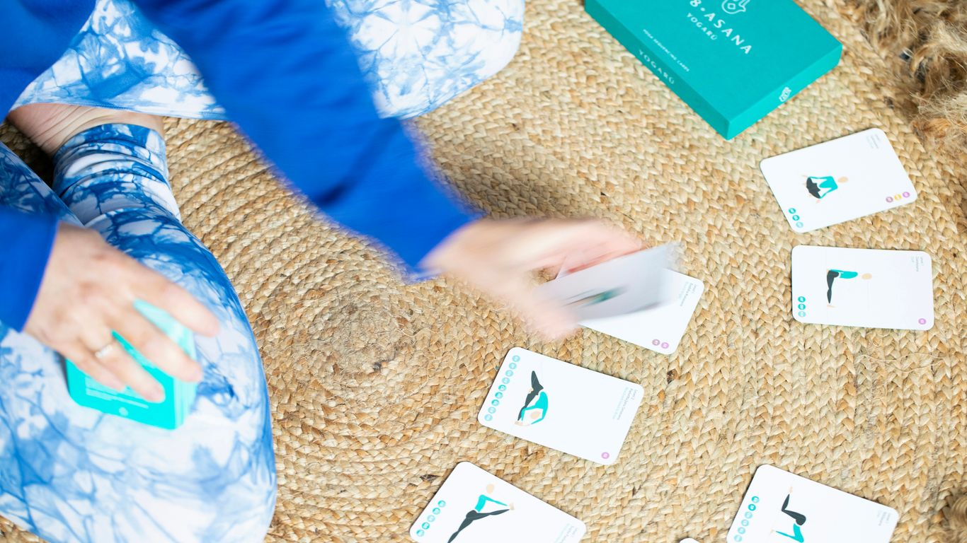 Person playing yoga cards on a mat.