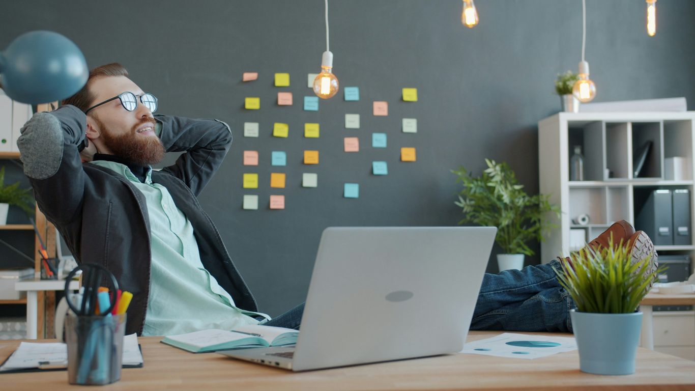 Man relaxing with feet on desk in office.