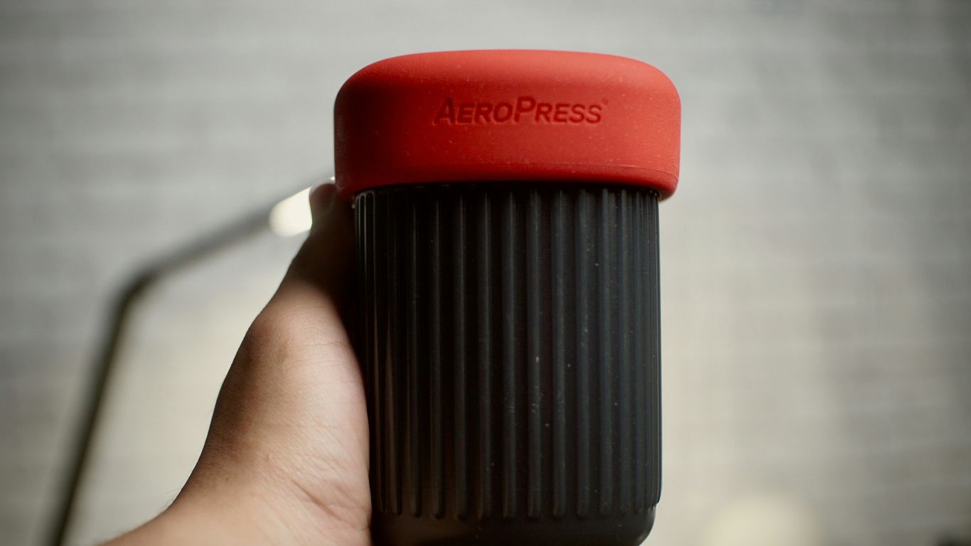 a hand holding a red and black coffee cup